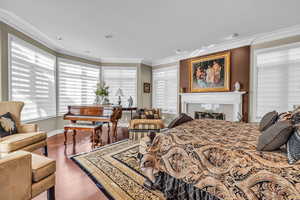 Master Bedroom featuring crown molding, a tile fireplace, and hardwood / wood-style floors