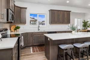 Kitchen with light hardwood / wood-style floors, stove, sink, and plenty of natural light