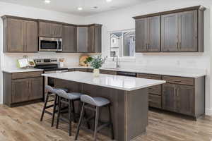 Kitchen featuring a center island, light hardwood / wood-style floors, dark brown cabinetry, and appliances with stainless steel finishes