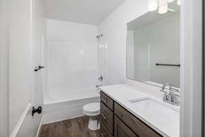 Full bathroom with shower / washtub combination, toilet, vanity, and hardwood / wood-style floors