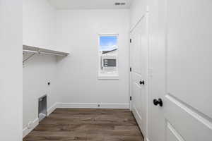 Laundry room featuring dark wood-type flooring and hookup for an electric dryer