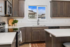 Kitchen featuring stainless steel appliances, wood-type flooring, dark brown cabinetry, and sink