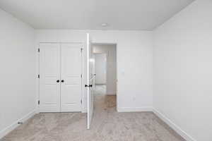 Unfurnished bedroom with a closet and light colored carpet