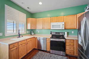 Kitchen with appliances with stainless steel finishes, dark hardwood / wood-style floors, and sink