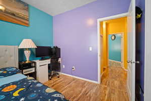 Bedroom with light wood-type flooring and a textured ceiling