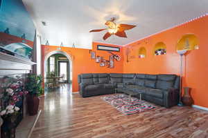 Living room featuring a textured ceiling, hardwood / wood-style floors, and ceiling fan