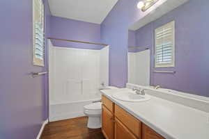 Full bathroom with shower / washtub combination, toilet, vanity, and hardwood / wood-style floors