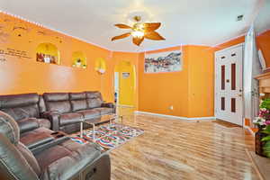 Living room with a textured ceiling, light wood-type flooring, and ceiling fan