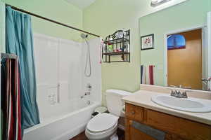 Full bathroom featuring shower / bathtub combination with curtain, toilet, and vanity