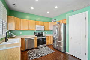 Kitchen featuring appliances with stainless steel finishes, light brown cabinetry, sink, and dark wood-type flooring