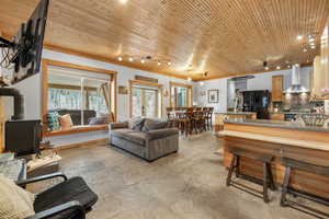 Living room with a wood stove, sink, and wood ceiling