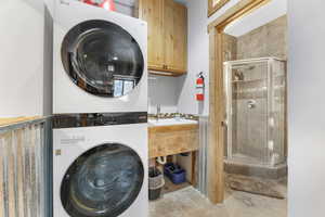 Washroom featuring cabinets and stacked washer and dryer