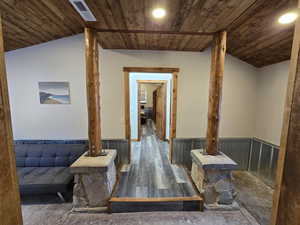 Hall with wood walls, dark hardwood / wood-style flooring, wood ceiling, and lofted ceiling