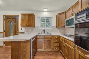 Kitchen with a breakfast bar, kitchen peninsula, appliances with stainless steel finishes, wood-type flooring, and sink