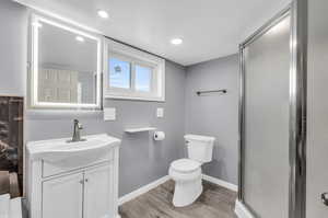 Bathroom featuring vanity, toilet, wood-type flooring, and walk in shower