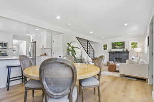 Dining area with light hardwood / wood-style flooring and a brick fireplace