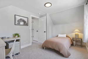 Bedroom with light carpet and vaulted ceiling