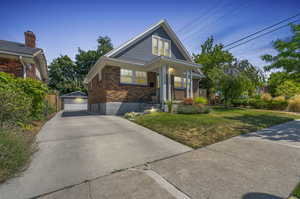 View of front of house with a garage, an outdoor structure, and a front yard