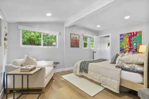 Bedroom featuring lofted ceiling with beams and light hardwood / wood-style flooring