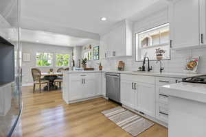 Kitchen featuring white cabinetry, dishwasher, backsplash, light hardwood / wood-style floors, and sink