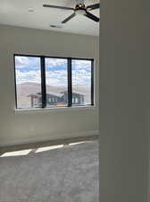 Carpeted spare room with a healthy amount of sunlight and ceiling fan