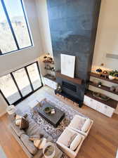 Living room with hardwood / wood-style floors, a high ceiling, and a tiled fireplace