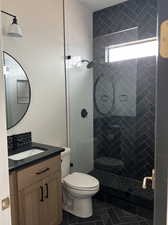 Bathroom featuring vanity, toilet, a tile shower, and tile patterned flooring