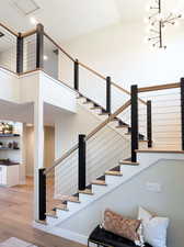 Stairway featuring an inviting chandelier, wood-type flooring, and a high ceiling