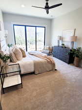 Carpeted bedroom featuring multiple windows and ceiling fan