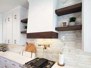 Kitchen featuring backsplash, light stone counters, and white cabinets