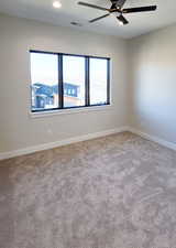 Empty room with ceiling fan and light colored carpet