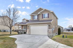 View of front facade featuring a front yard and a garage