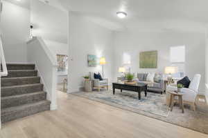 Living room featuring high vaulted ceiling and light hardwood / wood-style flooring