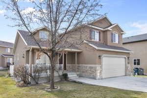 View of front of house with covered porch, a garage, and a front lawn