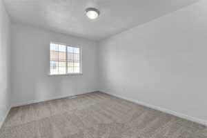 Carpeted empty room featuring a textured ceiling