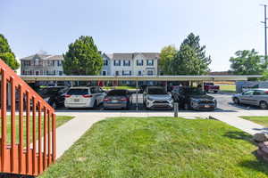 View of parking / parking lot with a yard and a carport