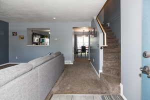 Hallway with a textured ceiling and carpet flooring