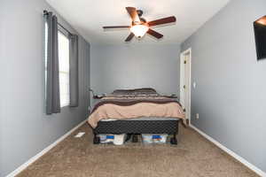 Carpeted bedroom featuring ceiling fan