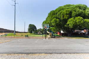 View of sport court with a playground and a lawn