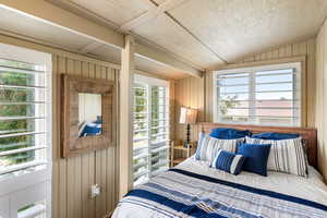 Bedroom with wooden walls and lofted ceiling