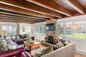 Living room with beamed ceiling, baseboard heating, and a healthy amount of sunlight