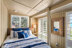 Bedroom with wood walls and lofted ceiling