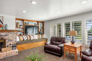 Living room featuring a fireplace, a textured ceiling, and carpet flooring