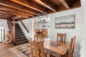 Dining room featuring beamed ceiling, wood ceiling, an inviting chandelier, and light hardwood / wood-style floors