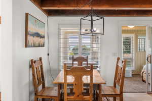 Dining space with beamed ceiling, light wood-type flooring, a notable chandelier, and a healthy amount of sunlight