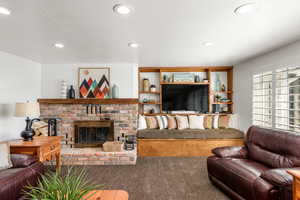 Living room with carpet flooring, a fireplace, and a textured ceiling