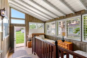 Sunroom featuring vaulted ceiling with beams and a healthy amount of sunlight