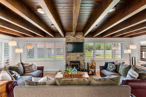 Living room featuring hardwood / wood-style floors, beamed ceiling, a baseboard heating unit, a brick fireplace, and wood ceiling