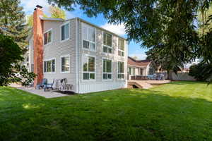 Back of property featuring a patio, a deck, and a lawn