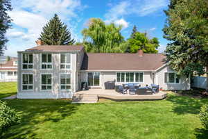 Back of property featuring a lawn, an outdoor living space, and a wooden deck